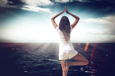 Eine Frau macht Yoga mit Blick auf das Meer